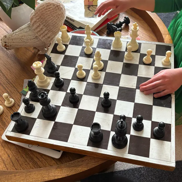 Photo of a worn wooden board on a round coffee table, seen from Black's side